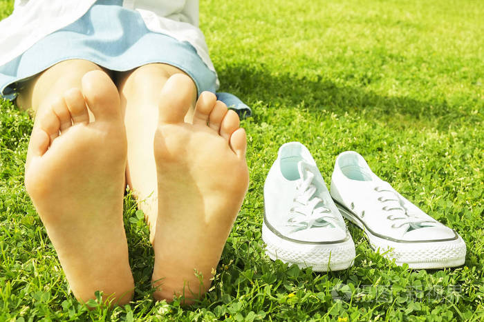 年轻女子赤脚在户外休息, 采取休息的概念.学生在大学校园围场