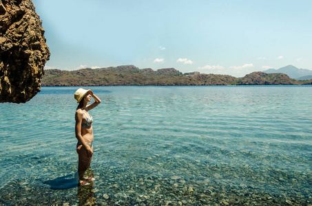 年轻的微笑的女人漂亮的运动苗条的身材在游泳套房做瑜伽自由运动站在蓝水绿松石泻湖景岛岩石海岸夏季健康假期