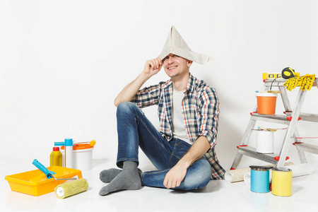 有趣的快乐微笑的人在报纸帽子坐在地板上, 装修的公寓房间被隔离在