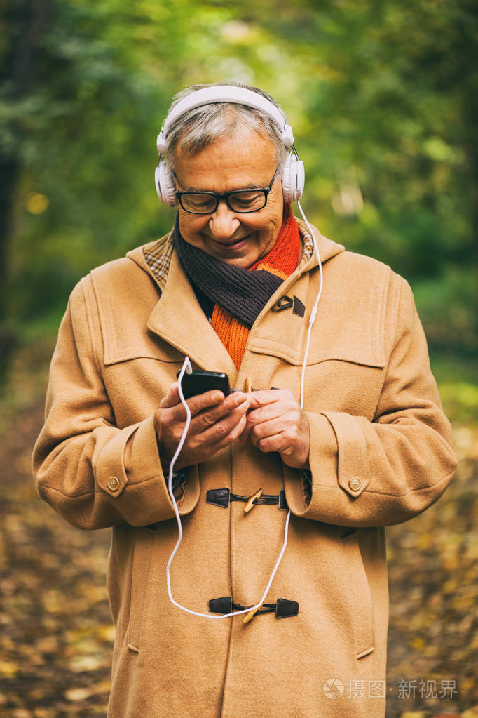 老人在秋天在公园听音乐.