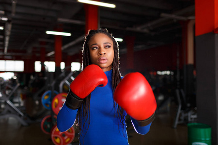 非洲美女拳击手在健身房训练穿着红色手套