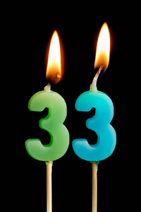 燃烧蜡烛的形式为33三十三 (数字, 日期) 的蛋糕孤立的黑色背景.