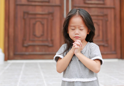 小亚洲女孩站在教堂祈祷. 双手折叠在祈祷的概念,信仰,灵性和宗教.