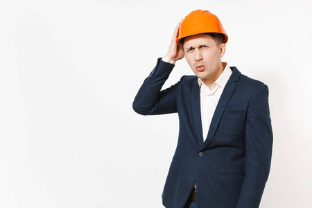 年轻英俊的商人在深色西装, 保护性建筑橙色头盔保持手在白色背景上的头部隔离。男性工作者为广告。业务工作理念