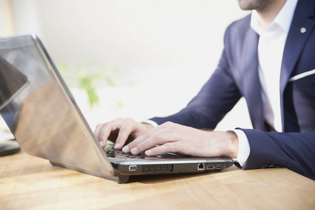 s hand typing on keyboard while sitting in front of laptop at th