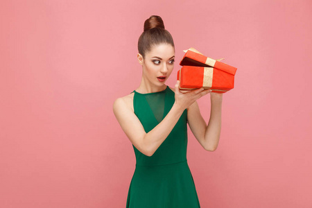 狡猾的女人打开红色礼品盒，看着里面的粉红色背景