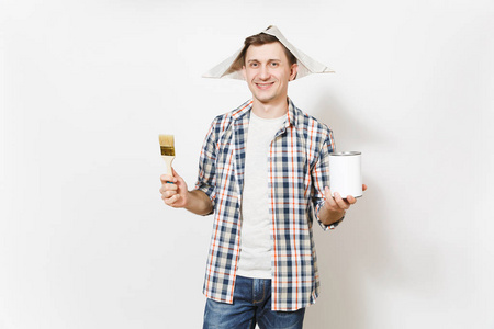 年轻的微笑英俊的男子在报纸帽子持有油漆刷和空漆锡可以与复制空间隔离在白色背景。翻新公寓房间的仪器。修复主页概念