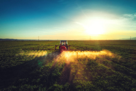 农用拖拉机田间耕作与喷洒的鸟瞰图照片