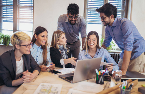 一群年轻的商务人士穿着智能休闲服,一起在创意办公室工作,使用笔记本