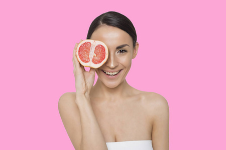 美味多汁的葡萄柚。 开朗的年轻美丽的女人手里拿着半个柚子，在相机上摆姿势。 柠檬酸和维生素促进健康