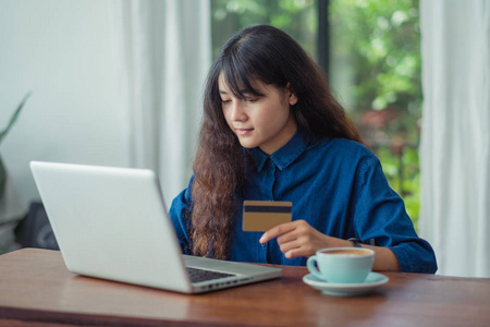 亚洲妇女网上购物使用信用卡与笔记本电脑计算机