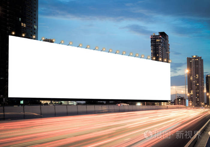 空白广告牌在公路上的黄昏与城市背景与剪裁路径的屏幕.