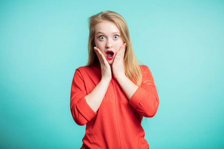 红色嘴唇的妇女惊奇地举行面颊用手.美丽的女孩震惊地看着你.