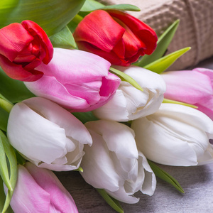 春天郁金香花粉红色礼品盒在老式灰色桌子上。 为女人或母亲节问候。