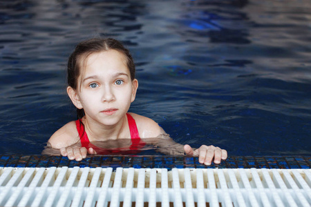一个年轻的女孩在池里用蓝色的水