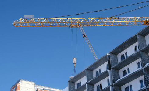 建筑工地上有起重机的天空背景。建造者在多层建筑的屋顶上工作。