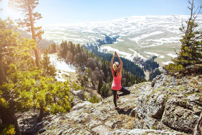年轻的女孩旅行者坐在山顶上的瑜伽姿势.这个女孩喜欢旅行.