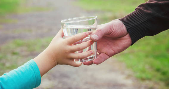 父亲给孩子一杯水。 选择性聚焦。