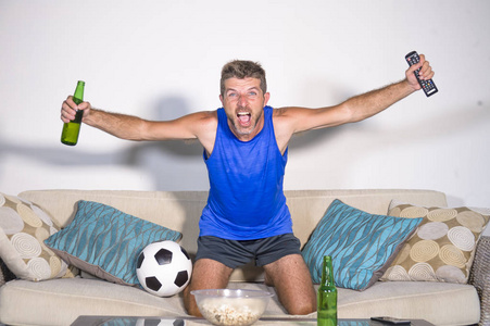 年轻有吸引力的人高兴和兴奋看足球比赛在电视庆祝胜利目标疯狂和痉挛与啤酒爆米花和足球