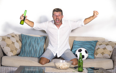 年轻有吸引力的人高兴和兴奋看足球比赛在电视庆祝胜利目标疯狂和痉挛与啤酒爆米花和足球