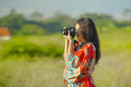 可爱的亚洲华人或韩国妇女在她的20s 拍摄照片与照片相机在美丽的自然景观在假期微笑快乐