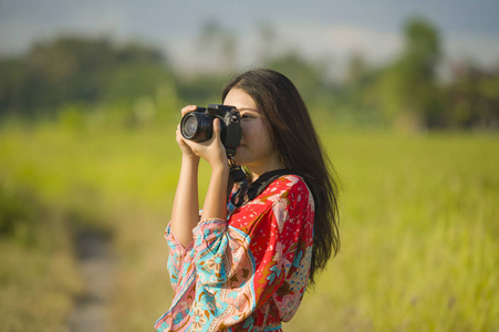 可爱的亚洲华人或韩国妇女在她的20s 拍摄照片与照片相机在美丽的自然景观在假期微笑快乐