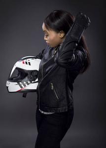 黑色女摩托车骑手或赛车司机戴着赛车头盔和皮夹克.