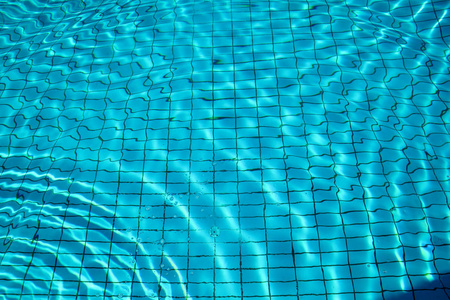 泳池底部焦线波纹和流动的波浪背景。蓝色游泳池的表面, 游泳池的水背景。清澈的浅蓝色水池水波纹与太阳反射
