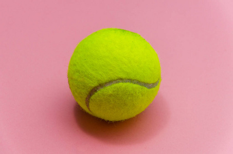 明亮的黄色网球在粉彩背景上关闭