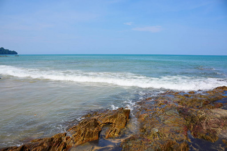 美丽的海滩，白色的波浪，岩石和白色的沙滩，渔船，微风，阳光明媚的一天。