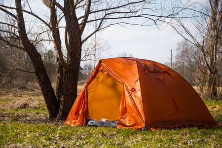 在河岸上建造的一个橙色帐篷。 春天的徒步旅行营。 早春的风景。