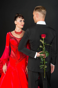 两个舞厅舞者相爱了的女人和男人隐藏玫瑰花。穿红衣服的女人, 穿着燕尾服的男人。情人节庆典。爱的建议和日期概念