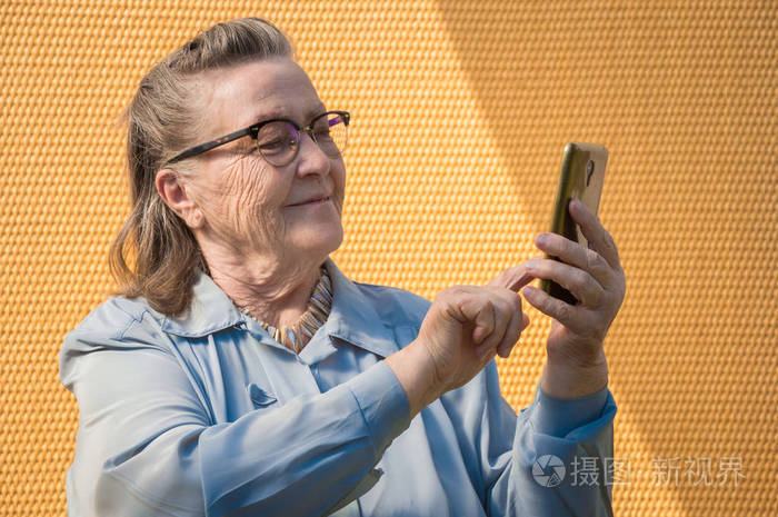 老妇人的画像, 祖母在阳光天使自拍户外活动。现代奶奶手指触摸触摸屏她的手机。她的成年手里有智能手机。技术生活方式