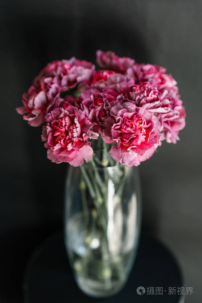 美丽的康乃馨花在桌子上的花瓶里.紫罗兰色, 紫色和粉红色的花的花束.