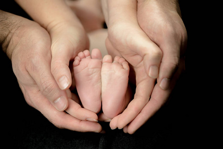新生婴儿双脚在父母手中幸福的家庭时刻父母与子女