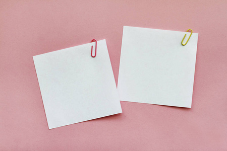 两张白色空白便签纸,带有浅粉色背景的剪辑照片