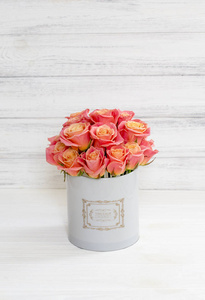 美丽的粉红色和黄色玫瑰在一个圆形盒子上的白色木制背景。