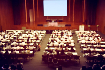 毕业典礼期间，学生观众的模糊形象和新生定向日或国际会议厅演讲的主旨发言人。 活动大学。 老式电影的颜色。