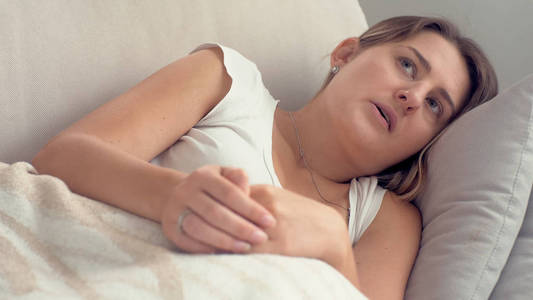 年轻女子躺在沙发上揉手感到紧张的照片