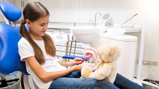 小女孩与泰迪熊在诊所的牙科诊所玩的肖像
