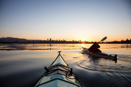在一个充满活力的阳光明媚的日出中，海上皮艇上的冒险女孩正在皮划艇。 被带到温哥华不列颠哥伦比亚省市中心。