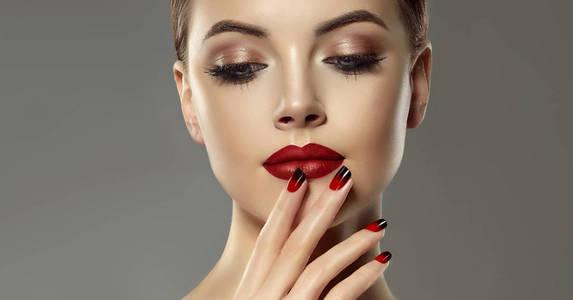 漂亮的模特女孩，指甲上有红色和黑色的法国指甲。 时尚豪华妆容。 樱桃色嘴唇和闪亮的眼影色素。 美容和化妆品。
