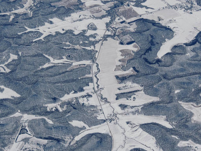 空中冬季雪景景观的农村和城市土地之间的明尼阿波利斯明尼苏达和印第安纳波利斯印第安纳，与积雪覆盖的田野，山丘和河床形成鲜明的对比。