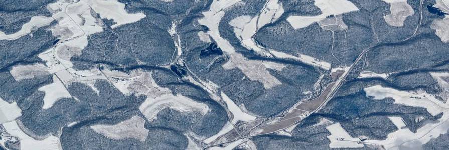 空中冬季雪景景观的农村和城市土地之间的明尼阿波利斯明尼苏达和印第安纳波利斯印第安纳，与积雪覆盖的田野，山丘和河床形成鲜明的对比。