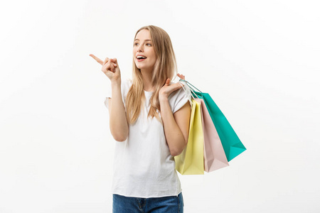 购物和生活方式的概念 年轻开朗的女人拿着五颜六色的购物袋和指着手指。通过白色背景隔离