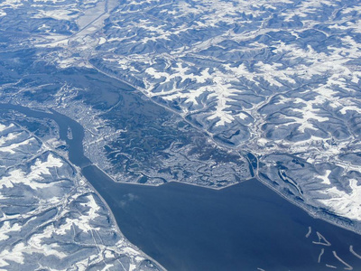 空中冬季雪景景观的农村和城市土地之间的明尼阿波利斯明尼苏达和印第安纳波利斯印第安纳，与积雪覆盖的田野，山丘和河床形成鲜明的对比。