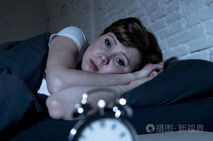 照片 年轻迷人的红头发的白种人女人深夜躺在床上,试图睡觉,患有失眠