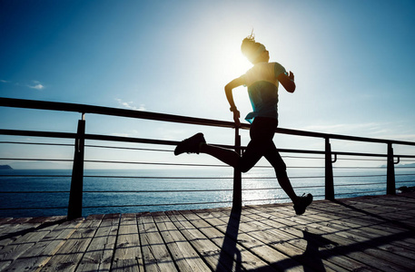 运动健身女跑步者日出时在海滨木板路上跑步照片