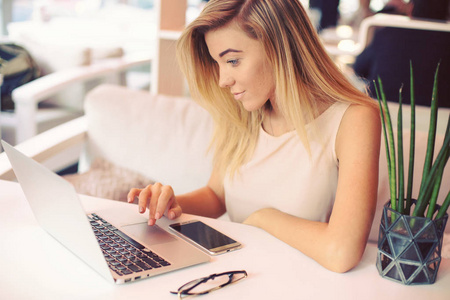 一个漂亮的年轻严肃的女商人早上在一个舒适的咖啡馆里做笔记本电脑。