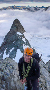 莫坦登山者在瑞士阿尔卑斯山的高山上从一座山峰走向另一座山峰，身后有一片云海